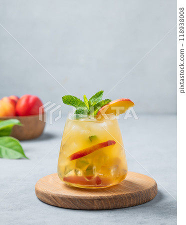 Refreshing peach cocktail, lemonade or iced tea on a wooden board on a light background. 118938008