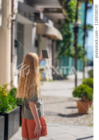 Young girl with long blonde hair taking selfie on street in city. Young girl with long blonde hair taking selfie on street in city. 118938030