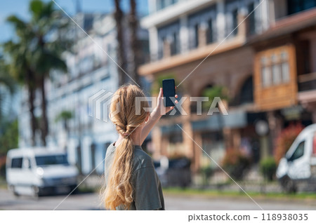 Young girl with long blonde hair taking selfie on street in city. 118938035