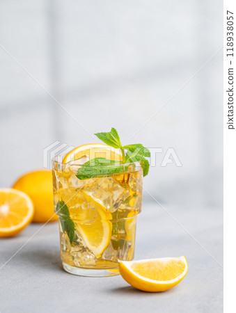 Iced tea with lemon, mint in a glass on light background with shadow and citrus fruits. 118938057