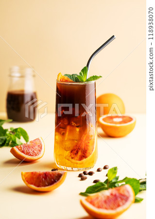 Americano coffee with orange juice (bumble) in a tall glass with ice and mint on a yellow background Americano coffee with orange juice (bumble) in a tall glass with ice and mint on a yellow background 118938070