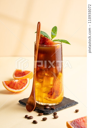 Espresso coffee with orange juice (bumble) in a tall glass with ice and mint on a yellow background Espresso coffee with orange juice (bumble) in a tall glass with ice and mint on a yellow background 118938072