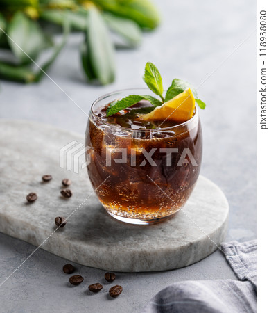 Coffee with tonic in a glass with mint, ice and lemon on a marble board on a light background 118938080