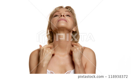Portrait of beautiful woman, middle-aged lady doing massage for neck against white studio background. Toned neckline. 118938372