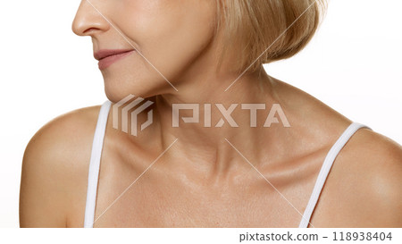 Profile view of smiling woman, showcasing natural lips and fine lines with glowing skin against white studio background. 118938404