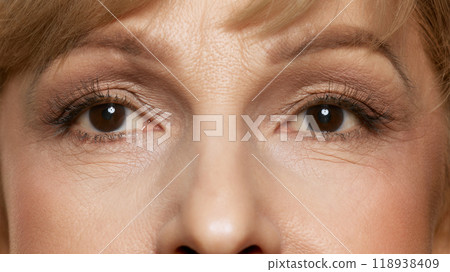 Expressive eyes. Close-up photo of middle ages woman's eyes with light make-up against white studio background. Mimicable wrinkles. 118938409