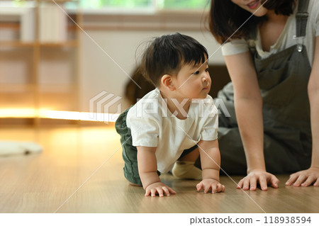 Mother watching her cute baby boy crawling on floor. Childhood and development concept 118938594