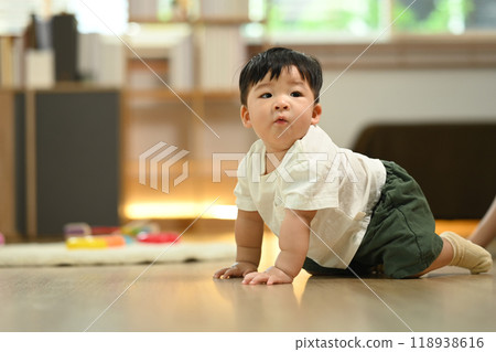 Adorable baby boy crawling on the floor in living room, exploring his surroundings. Child development concept 118938616