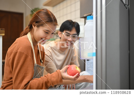Young couple picking up some fruit from the fridge to making healthy breakfast Young couple picking up some fruit from the fridge to making healthy breakfast 118938628