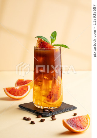 Espresso coffee with orange juice (bumble) in a tall glass with ice and mint on a yellow background Espresso coffee with orange juice (bumble) in a tall glass with ice and mint on a yellow background 118938687