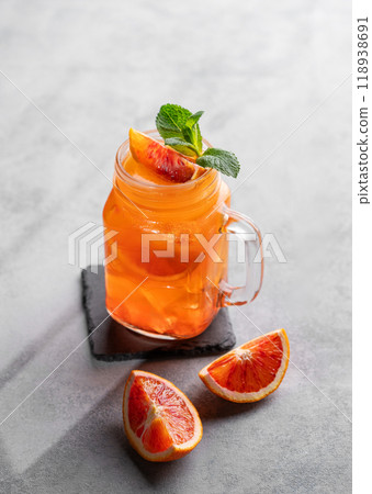 Freshly squeezed blood orange juice with ice, mint and a slice of fruit in a jar on blue background Freshly squeezed blood orange juice with ice, mint and a slice of fruit in a jar on blue background 118938691