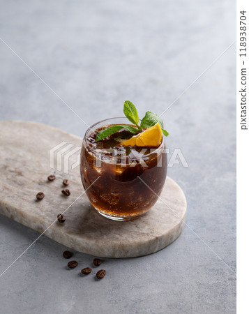 Coffee espresso with tonic in a glass with mint and lemon on a marble board on a light background 118938704