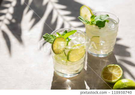 Two glasses with lime lemonade with mint and ice. Refreshing mojito cocktail with citrus fruitsc 118938740