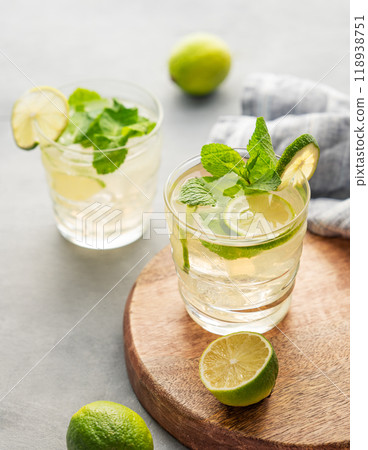 Two glasses lime mojito with mint and ice on a wooden board. Refreshing citrus cocktail Two glasses lime mojito with mint and ice on a wooden board. Refreshing citrus cocktail 118938751