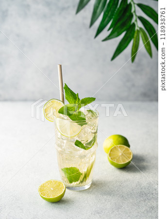 Mojito cocktail in a tall glass with lime, mint and ice on a light background.  118938761
