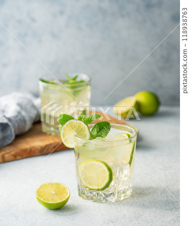 Two glasses mojito cocktail with lime, mint and ice on a light background. Two glasses mojito cocktail with lime, mint and ice on a light background. 118938763