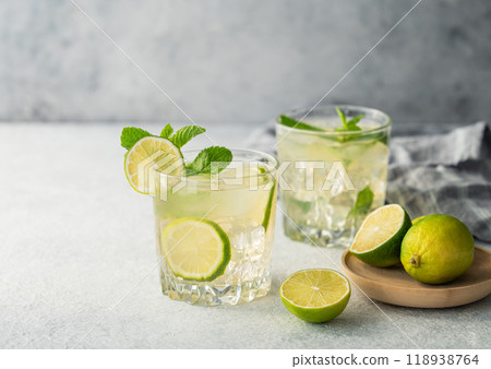Two glasses mojito cocktail with lime, mint and ice on a light background. Two glasses mojito cocktail with lime, mint and ice on a light background. 118938764