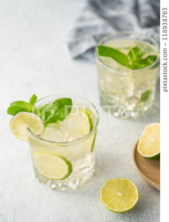 Two glasses lime cocktail with fresh citrus fruits on a light background. Two glasses lime cocktail with fresh citrus fruits on a light background. 118938765
