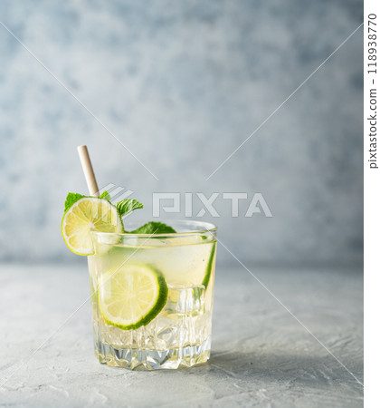 Mojito drink with fresh lime on a texture blue background. Refreshing cocktail with citrus fruits Mojito drink with fresh lime on a texture blue background. Refreshing cocktail with citrus fruits 118938770