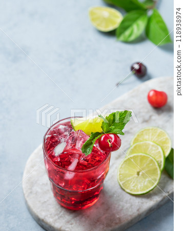 Cherry-lime mojito cocktail with mint, lime and ice on a marble board on a light background. Cherry-lime mojito cocktail with mint, lime and ice on a marble board on a light background. 118938974