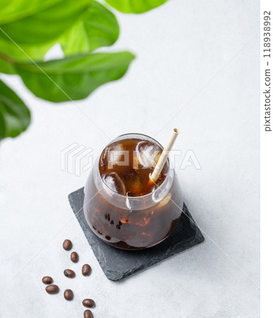 Coffee espresso in a glass with ice on a black board on a light background with coffee beans  118938992