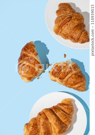 Flat lay of fresh croissants on blue background with shadow. Creative layout and concept of food Flat lay of fresh croissants on blue background with shadow. Creative layout and concept of food 118939015