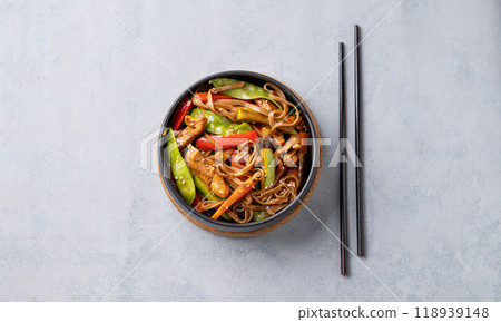 Stir-fry with soba noodles, meat and vegetables in black plate on a light background. 118939148