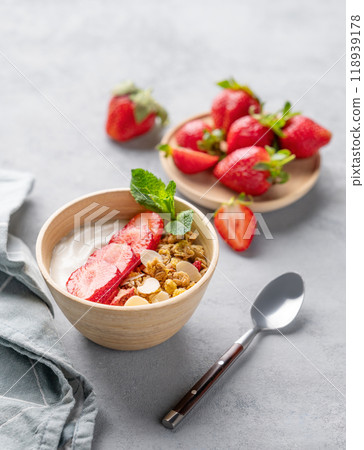 Natural greek yogurt with granola and strawberries in a bowl on a blue background with fresh berries 118939178