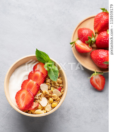 Natural yogurt with granola and strawberries in a bowl on a blue background with fresh berries. Natural yogurt with granola and strawberries in a bowl on a blue background with fresh berries. 118939179
