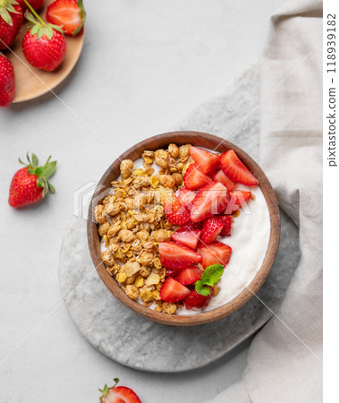 Natural yogurt with granola and strawberries in a wooden bowl on a marble board on  light background 118939182
