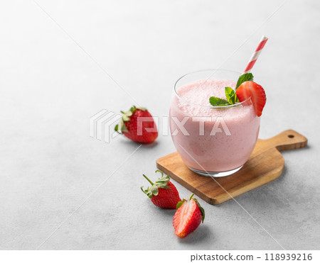 A glass of fresh strawberry smoothie with mint on a wooden board on a light background A glass of fresh strawberry smoothie with mint on a wooden board on a light background 118939216