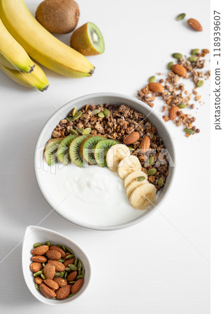 Granola and milk product with banana and kiwi on a white table. Granola and milk product with banana and kiwi on a white table. 118939607