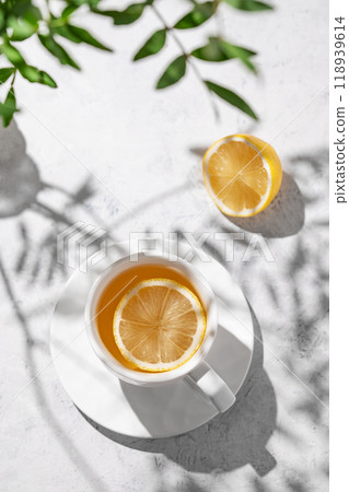 A cup of tea with lemon and green branch on a white table.  Breakfast detox and healthy concept. 118939614