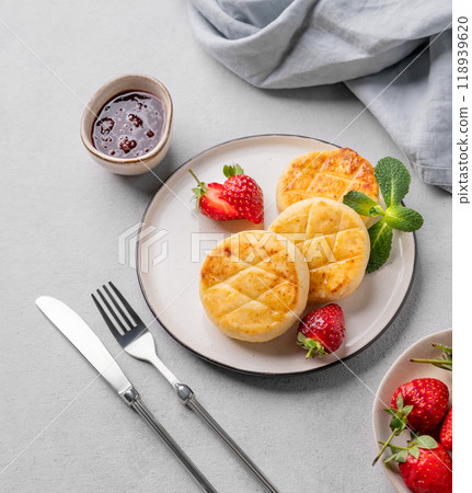 Cottage cheese, cheesecakes or syrniki with strawberries, berry jam and mint leaves on a white plate Cottage cheese, cheesecakes or syrniki with strawberries, berry jam and mint leaves on a white plate 118939620