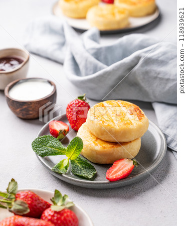 Cottage cheese, cheesecakes or syrniki with strawberries, sour cream, berry jam and mint leaves Cottage cheese, cheesecakes or syrniki with strawberries, sour cream, berry jam and mint leaves 118939621