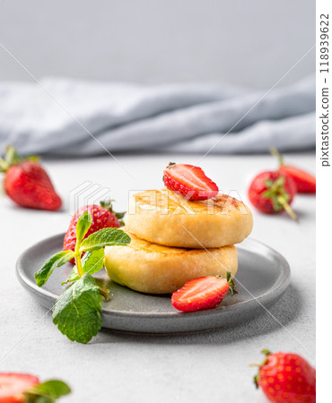 Cottage cheese, cheesecakes or syrniki with strawberries and mint leaves on a gray plate Cottage cheese, cheesecakes or syrniki with strawberries and mint leaves on a gray plate 118939622