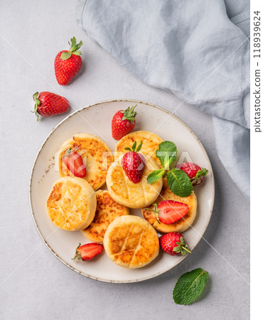 Cottage cheese, cheesecakes or syrniki with strawberries and mint leaves on a white plate Cottage cheese, cheesecakes or syrniki with strawberries and mint leaves on a white plate 118939624