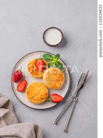 Cottage cheese, cheesecakes or syrniki with strawberries and mint leaves on a white plate Cottage cheese, cheesecakes or syrniki with strawberries and mint leaves on a white plate 118939632