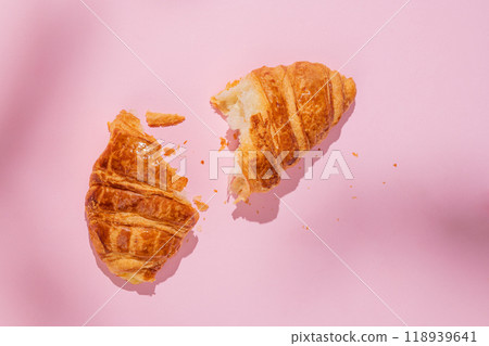 Flat lay of fresh broken croissant on pink background with shadow. Flat lay of fresh broken croissant on pink background with shadow. 118939641