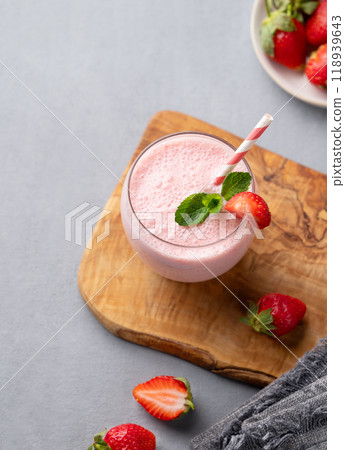 A glass of fresh strawberry smoothie with mint on a wooden board on a blue background A glass of fresh strawberry smoothie with mint on a wooden board on a blue background 118939643