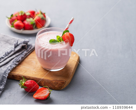 A glass of fresh strawberry smoothie with mint on a wooden board on a blue background  118939644