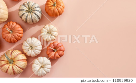 Colorful pumpkins arranged artistically on a light peach background for seasonal decoration during autumn festivities 118939920