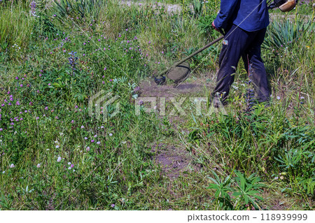 A man cuts and mows the grass. Grass cutting work. Worker mows lawn with grass A man cuts and mows the grass. Grass cutting work. Worker mows lawn with grass 118939999
