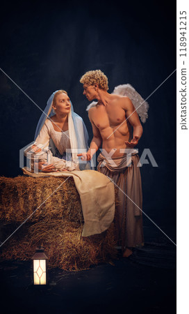 Christmas nativity scene with Mary holding baby Jesus and angel standing near against black background. Holy night. Christmas nativity scene with Mary holding baby Jesus and angel standing near against black background. Holy night. 118941215