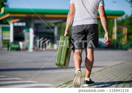 Confident man with canister finally found petrol station. Young male with empty canister in hand on background of gas station. Confident man with canister finally found petrol station. Young male with empty canister in hand on background of gas station. 118941216