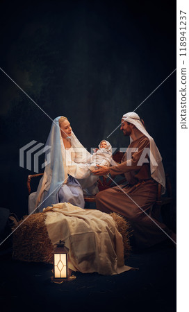 Holy and magical nativity scene with Mary gently holding baby Jesus with wise man, Joseph and shepherd standing around 118941237
