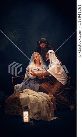 Tender significant moment. Holy and magical nativity scene with Mary gently holding baby Jesus with wise man, Joseph and shepherd standing around 118941261