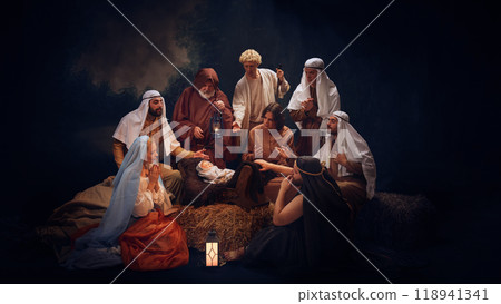 The Holy Family and wise men gather in prayer around baby Jesus. Hope and the light of salvation on Christmas night. 118941341