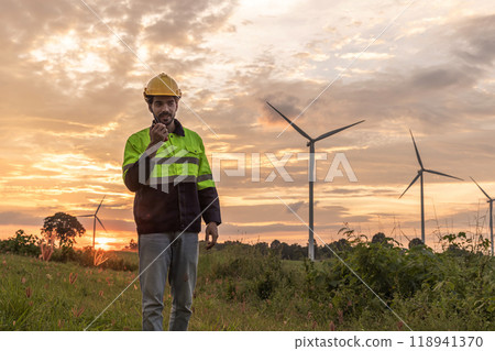 Professional Man Maintenance engineers working in wind turbine farm at sunset.  Engineer Man standing among Wind Energy Turbine. 118941370
