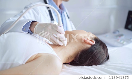 Doctor man is using ultrasound equipment on neck of female patient lying down for a medical examination. Medicine and science 118941875